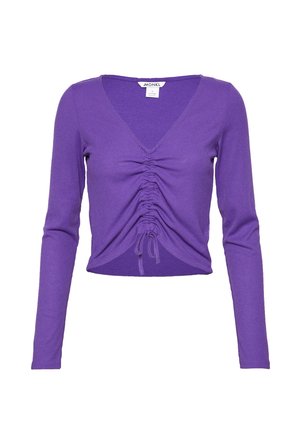 Haut court violet à manches longues avec encolure en V et devant froncé noué avec cordon de serrage réglable, tissu en maille côtelée.