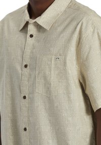 Korte mouwen, lichtbeige knoopshirt met een gestructureerd patroon van geometrische vormen en een borstzak met een logo-label.