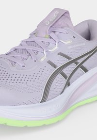Ανοιχτό μωβ αθλητικό παπούτσι Asics Gel-Cumulus 28 με γκρι ρίγες, λευκή ενδιάμεση σόλα και ανοιχτό πράσινο εξωτερικό πέλμα, που δείχνει λεπτομερή πλέγμα και κορδόνια.