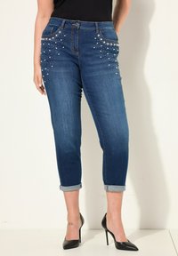 Dunkelblaue Denim-Jeans mit dekorativen Perlenverzierungen auf der Vorderseite und umgeschlagenen Säumen. Klassischer 5-Pocket-Stil.