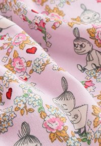 Svetloružová látka so kvetinovým vzorom s malými čiernymi a bielymi postavičkami, tvarmi srdca a rôznymi farebnými kvetmi po celom povrchu.