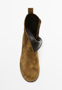 Braune Wildleder-Stiefelette mit Lederbesatz, am oberen Rand leicht umgeschlagen. Verfügt über eine Schlaufe für ein einfaches Anziehen und eine glatte, matte Textur.