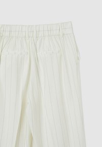 I pantaloni a righe verde chiaro presentano una vita elastica, due tasche posteriori e una texture liscia, evidenziando un design su misura.