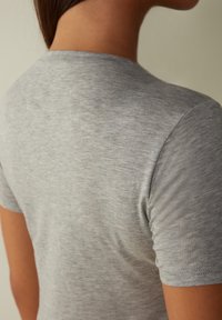 Grå t-shirt med kort ärm, tillverkad av mjuk, texturerad kvalitet. Har en klassisk rund halsringning och sömlösa axelsömmar.