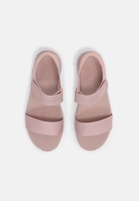 Sandali rosa chiaro con due ampi strappi in tessuto e una soletta imbottita. Presentano il marchio Skechers impresso sulla soletta. Texture liscia.