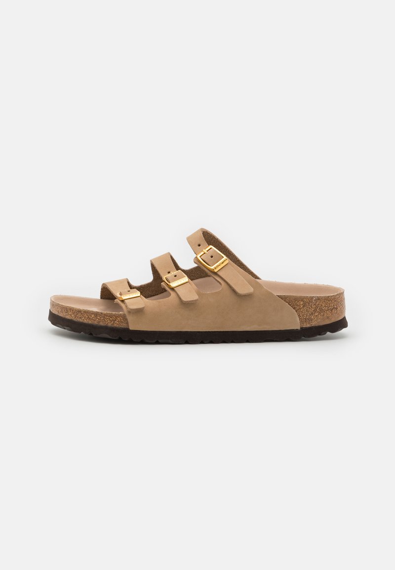 Sandal slide em camurça bege com três tiras ajustáveis, detalhes em hardware dourado e uma sola de cortiça com um fundo de borracha escura.
