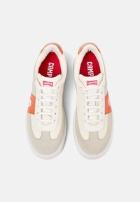 Sneakers med en krämfärgad ovandel, orange detaljer och en röd innersula, med en texturerad design, rund tåform och traditionell snörning.
