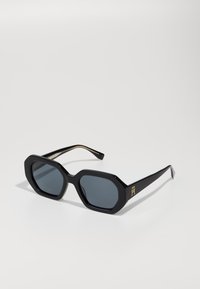 Black octagonal sunglasses with dark lenses and gold hardware accents on the temples, featuring a smooth, glossy plastic frame.