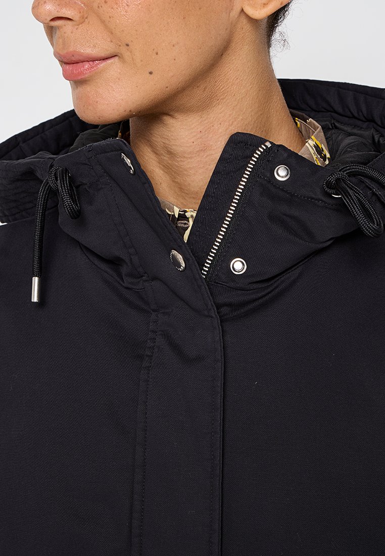 Zwarte hooded jacket met trekkoorden, zichtbare rits en drukknoopjes. Heeft een gladde textuur en stevig materiaal.