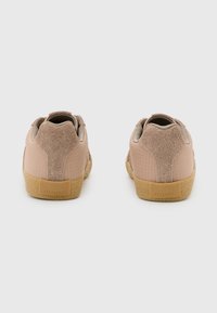 Sneakers con una toma superiore in tessuto e suede rosa chiaro, dettagli testurizzati e una suola in gomma beige. Presentano il logo del marchio sul tallone.