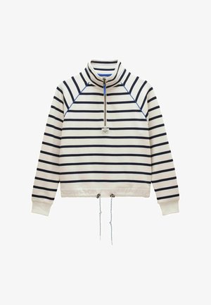 Balta megztinio tipo palaidinė su tamsiai mėlynomis horizontaliomis juostelėmis, ketvirčio užtrauktuku prie kaklo, mėlynomis siūlėmis, ribiniais rankogaliais ir reguliuojamu raišteliu apačioje.