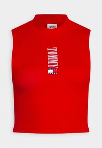 Red sleeveless crop top made of ribbed fabric featuring vertical white embroidered "TOMMY" logo and brand name at the center.