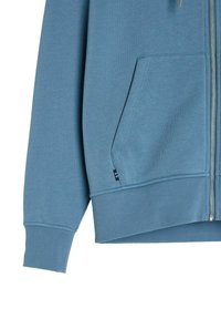 Niebieska bluza z zamkiem błyskawicznym, wykonana z miękkiego materiału. Posiada przednią kieszeń, ściągacze na rękawach i u dołu. Srebrny zamek ze zdobnym przeszyciem.