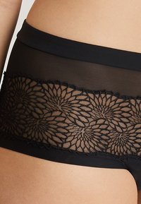 Lencería negra con una cinta de encaje transparente con patrones florales. La tela principal es suave, con una cintura elástica para mayor comodidad.