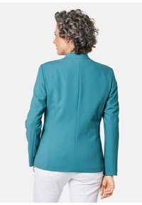 Teele blazer met een getailleerde pasvorm, gestructureerde schouders en lange mouwen. Heeft een schone achternaad en minimale details, gecombineerd met witte broek.