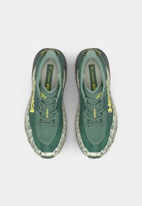 Zöld Hoka Speedgoat 6 sportcipők lélegző felsőrésszel, textúrált hálós anyaggal, sárga logóval és mintás fehér középtalppal a párnázás érdekében.