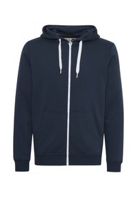 Sudadera con cremallera en azul marino, con capucha ajustable mediante cordón, bolsillos frontales y cremallera blanca. Fabricada en un tejido suave y elástico.