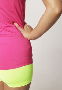 Haut ajusté rose en Dri-FIT à manches courtes, associé à un short taille haute vert néon. Texture lisse et détails de design sans couture.