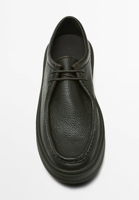 Chaussure en cuir noire avec une surface texturée, bout rond, couture minime et semelle en caoutchouc plate. Fermeture à lacets avec des accents lisses.
