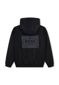 Veste à capuche noire avec des poignets et un ourlet élastiques, présentant un grand patch logo "BOSS" au centre du dos.