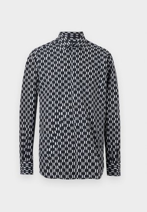 Sort skjorte med krave og lange ærmer med hvidt geometrisk lynmønster, knapper ved manchetter og knaplukning foran.