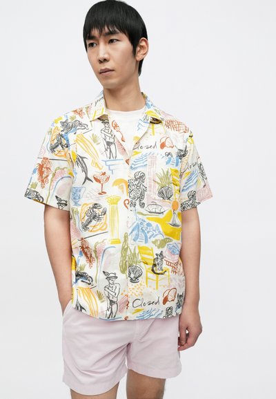 Πουκάμισο με κουμπιά μπροστά και πολύχρωμα γραφικά σχέδια που περιλαμβάνουν στοιχεία όπως ζώα και φυτά. Κοντά μανίκια και άνετη γραμμή σε ελαφρύ ύφασμα.