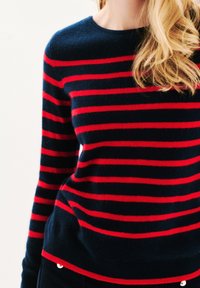 Dunkelblauer Pullover mit roten horizontalen Streifen, Rundhalsausschnitt und langen Ärmeln. Weicher Stoff, gerippter Saum und taillierte Passform.