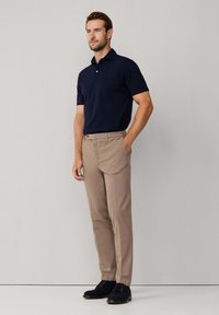 Granatowa koszulka polo, khaki spodnie i czarne sznurowane buty. Gładki materiał, standardowy krój, krótkie rękawy i klasyczny kołnierzyk.