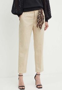 Pantaloni beige realizzati in un tessuto leggero, con una vestibilità rilassata, lunghezza cropped e una sciarpa a stampa leopardo legata in vita.