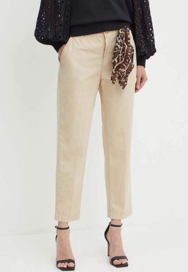 Pantaloni beige realizzati in un tessuto leggero, con una vestibilità rilassata, lunghezza cropped e una sciarpa a stampa leopardo legata in vita.