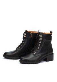 Black leather ankle boots with lace-up fronts, side zippers, gold eyelets, low block heels, and detailed stitching on a white background.