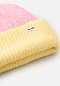 Kleurvolle gebreide beanie met een roze bovenstuk en een getextureerde gele geribde manchet; inclusief een klein wit label met het "RIPCURL" logo.