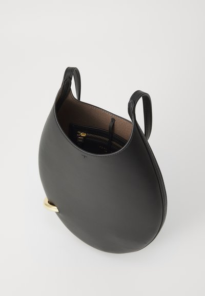 Fekete bőrtáska kerek formával, sima felülettel, két füllel és arany színű fém díszítéssel. A belsejében egy cipzáras zseb található.