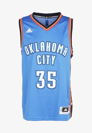 Hombre con camiseta y pantalones cortos de baloncesto azul de Oklahoma City con el número 35, caminando hacia adelante con zapatillas blancas de caña alta.