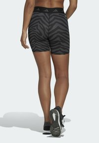 Svarta och grå zebra-mönstrade shorts med hög midja, gjorda av ett slätt, stretchigt material, i kombination med svarta träningsskor.
