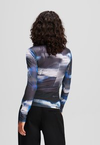 Strak zittende langekleurige top met een blauw en zwart abstract patroon, gemaakt van een soepele, rekbare stof met een slank ontwerp.