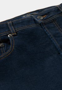 Jeans in denim blu scuro con cuciture arancioni a contrasto. Caratteristiche includono una tasca frontale standard, bottone in metallo e un'etichetta sulla vita.