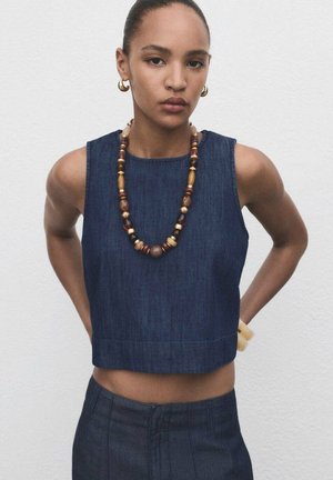 Džínový crop top s kulatým výstřihem, bez rukávů. Doplněný barevným náhrdelníkem z korálků a přírodním dřevěným náramkem.
