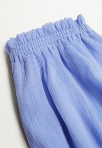 Světle modrá, texturovaná tkanina s nařaseným elastickým pasem, s navršenými detaily a splývavou drapérií, zdůrazňujícími jemnost a pohyb.