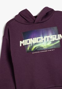 Lila hoodie med en framsida som har grafiken "MIDNIGHT SUN" och en aurora-design. Mjuk tyg, långa ärmar och huva.