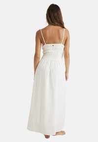 Abito maxi bianco con corpetto arricciato, spalline sottili e tessuto fluido con una finitura testurizzata. Senza decorazioni visibili.
