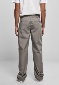 Gray, straight-leg trousers with a smooth texture, rear pockets, and a standard waistband, paired with black-laced shoes.
