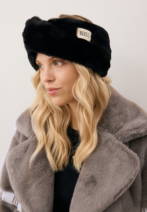 Czarny futrzany opaska na głowę z twisted designem i prostokątną kremową metką z napisem "BIZUU". Miękka tekstura, dopasowany krój zwiększa ciepło.