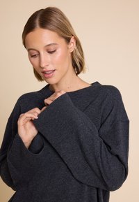 Mørkegrå, oversized genser med lange ermer, bred utringning, ribbestrikkede mansjetter og myk tekstur. Minimalistisk design, sitter behagelig.