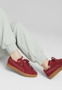 Zapatillas de ante rojo con suela de goma, con detalles y cordones blancos. Diseñadas con un perfil bajo y punta redondeada.