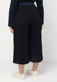 Culotte blu scuro con pois bianchi, vestibilità ampia, elastico in vita, lunghezza cropped, abbinate a sneakers bianche.