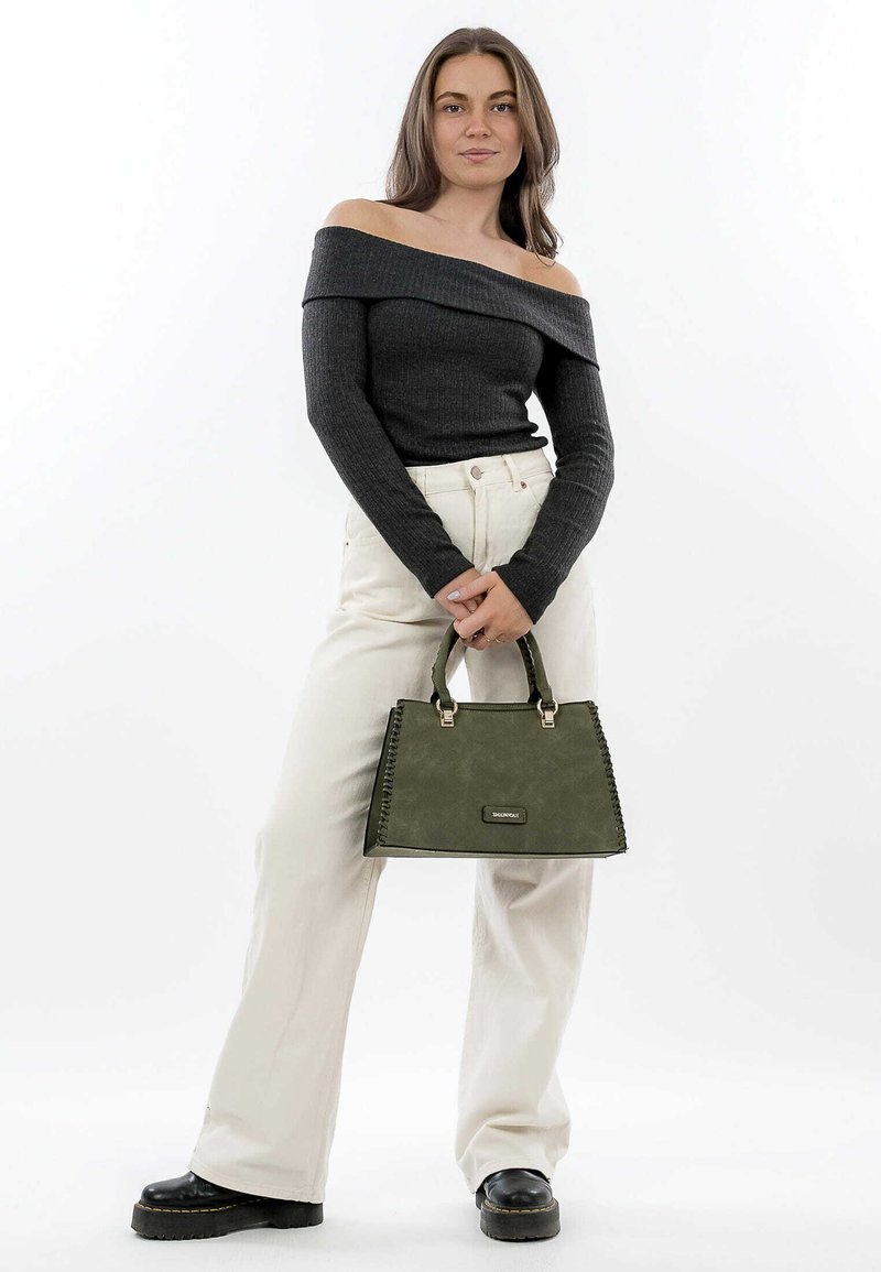 Green handbag with a smooth texture, rectangular shape, and decorative stitching. Model wears a dark off-the-shoulder top and light pants.