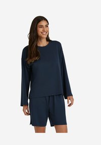 Dunkelblaue Loungewear-Kombination mit einem langärmeligen Oberteil und rundem Halsausschnitt sowie passenden Shorts. Weicher Stoff mit entspanntem Schnitt.