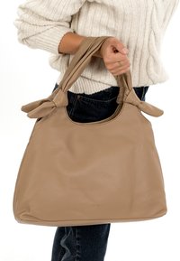 Beige Ledertasche mit geknoteten, weichen Griffen. Die Tasche hat eine strukturierte Oberfläche und ein geräumiges Design. Keine sichtbaren Metallteile oder Verzierungen.