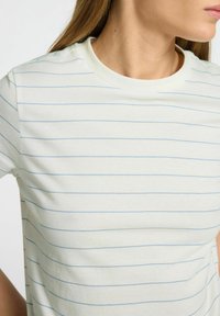 Kortärmad t-shirt med rund hals i ljus krämfärgad tyg med tunna blå horisontella ränder, som har en slät yta och klassisk passform.